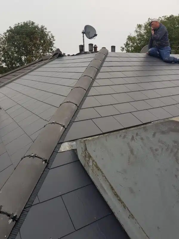 Newly installed dark grey tiled roof with new ridge tiles