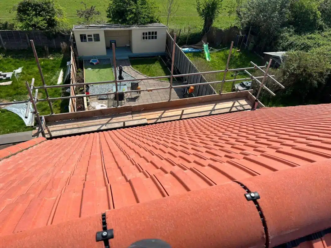 Re-roofing a pitched roof with terracotta-red concrete tiles, scaffolding still in place