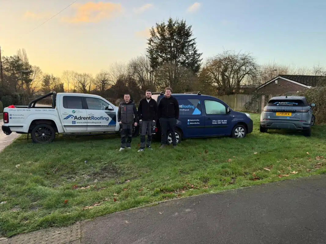 The Adrent Roofing team standing in front of our service vans
