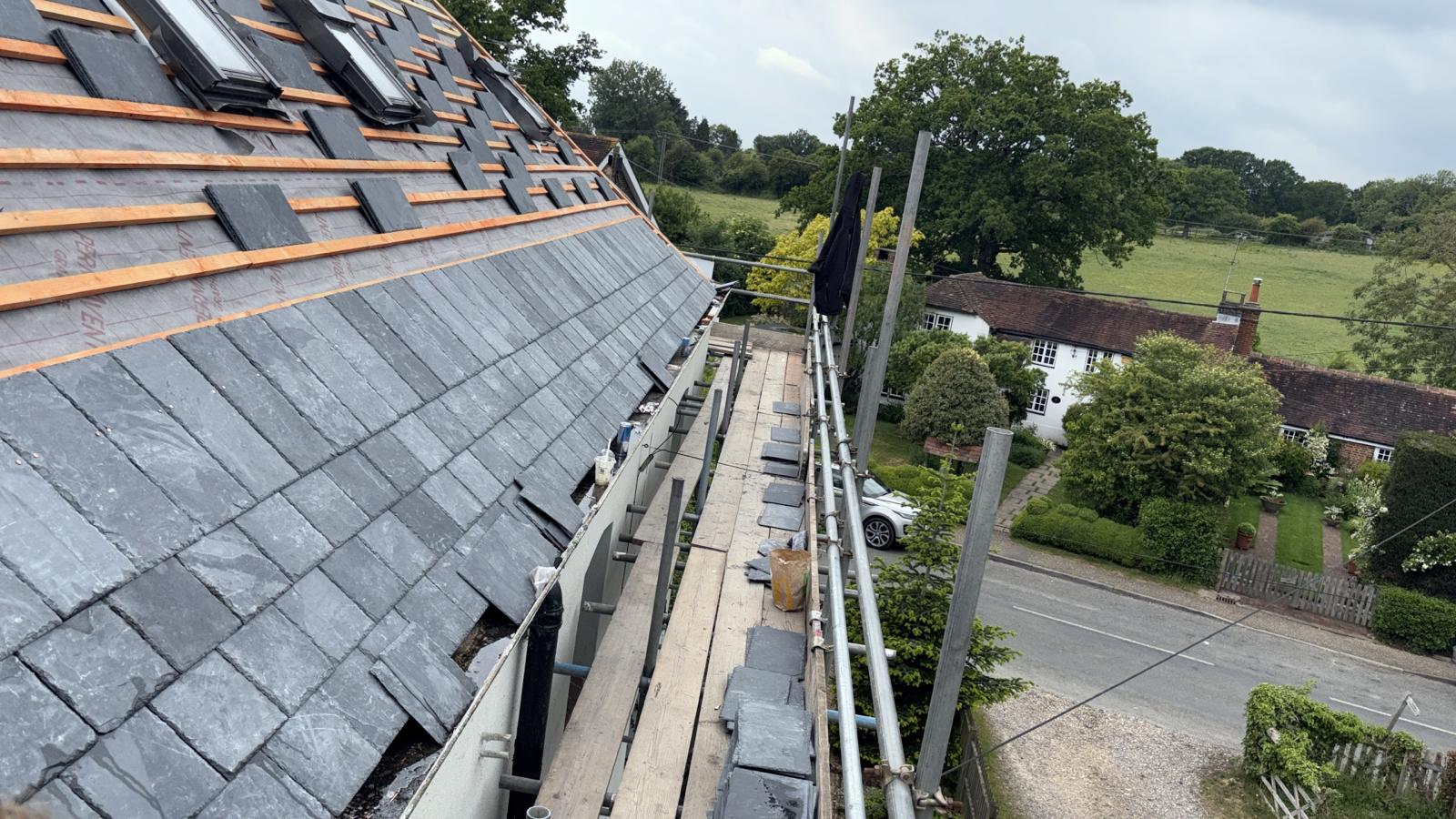 Slate roof with rooflights and full scaffolding running along the eaves