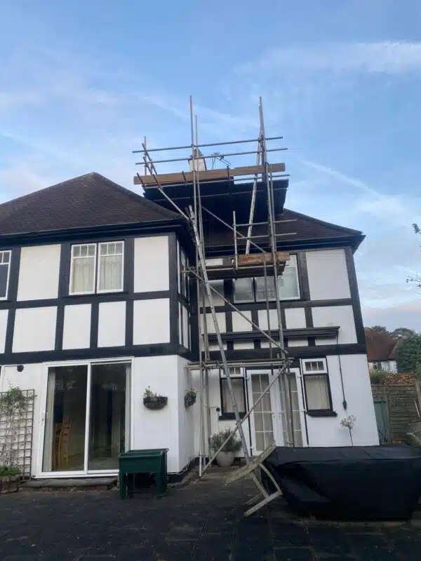 Scaffolding erected for chimney repairs on a dark brown clay-tile roof
