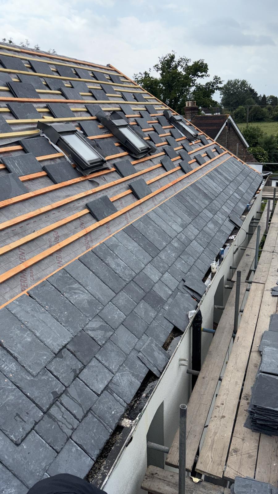 Natural slate roof being laid around three new roof windows