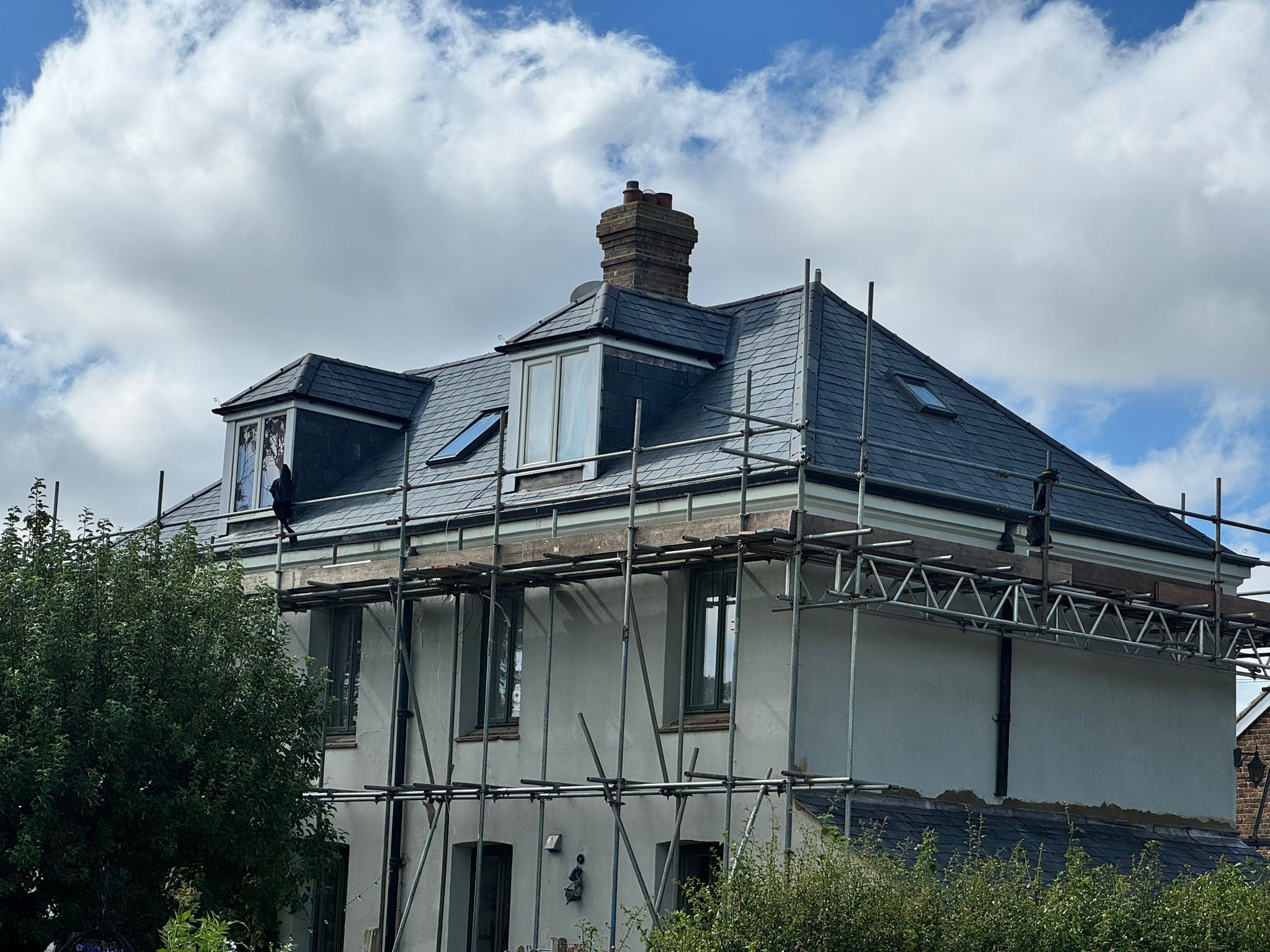 Newly re-slated hipped roof with dormer windows and scaffolding still standing