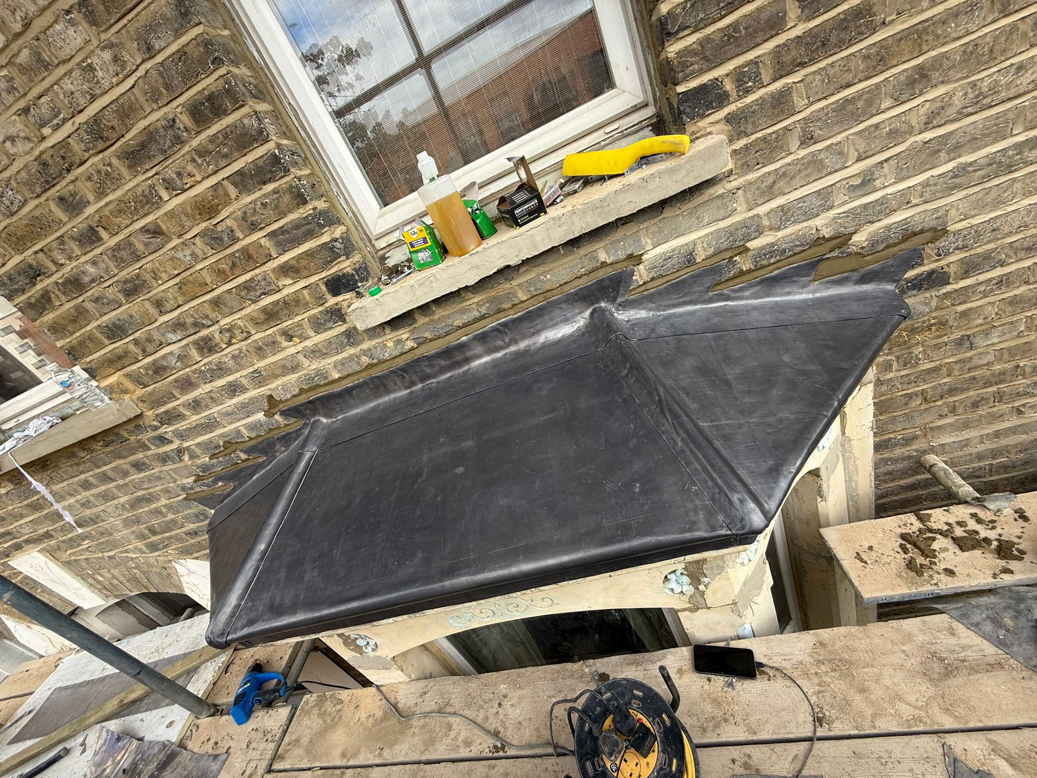 Bespoke lead canopy over a canted bay window with stepped lead flashing into the brickwork