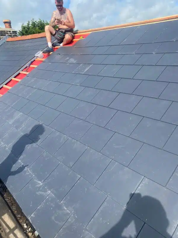 New slate tiles being laid over red underlay and fresh battens