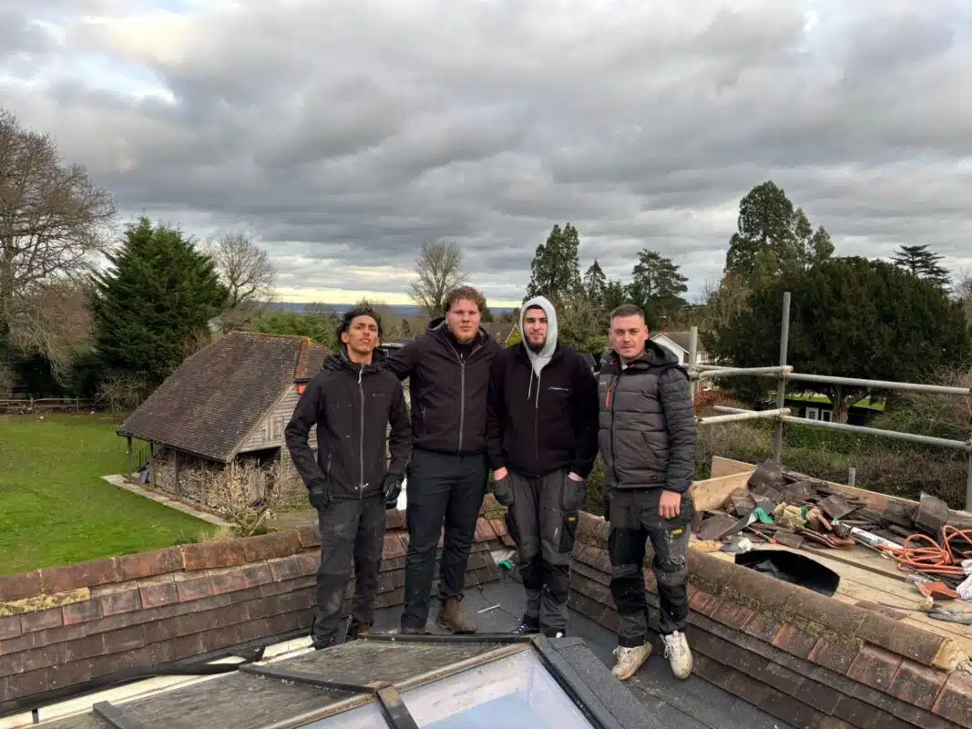 Repairing reddish-brown clay roof tiles with scaffolding in place