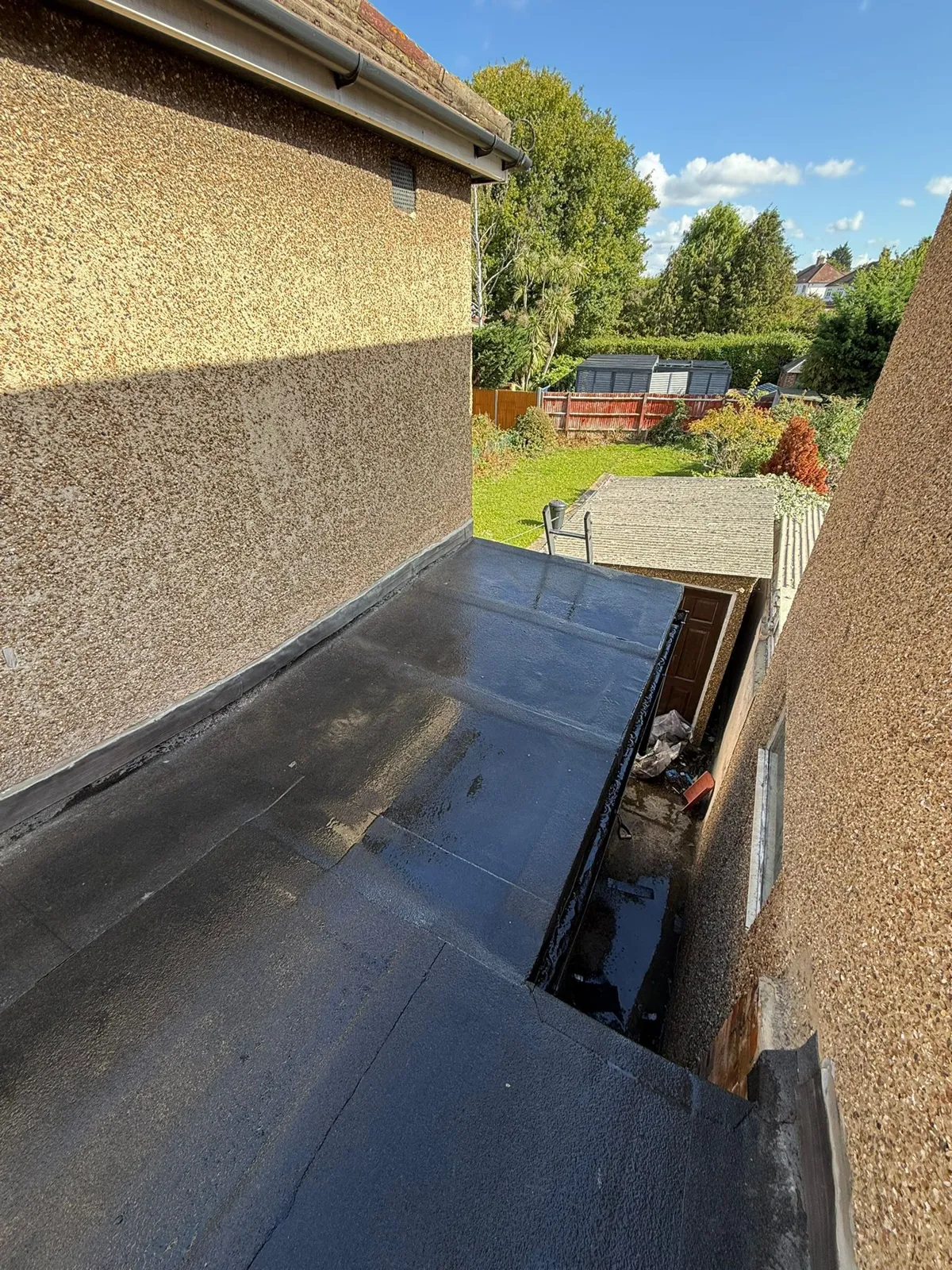 Completed mineral-finish flat roof on an extension with lead flashing into the wall