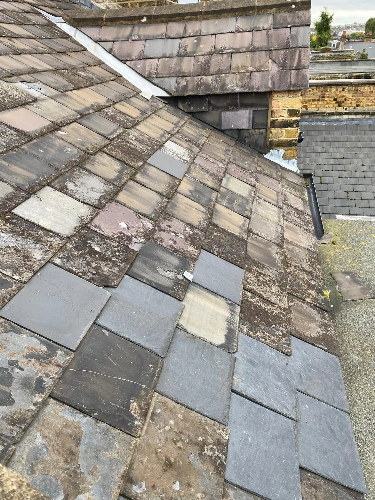 Period brick chimney stacks with pots on a Victorian slate roof