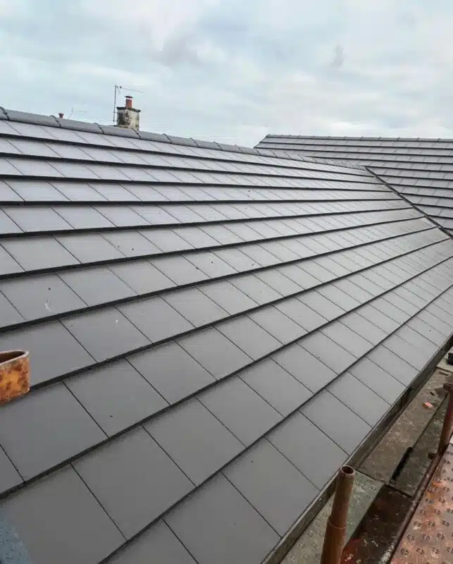Newly finished pitched roof laid with dark grey interlocking concrete tiles